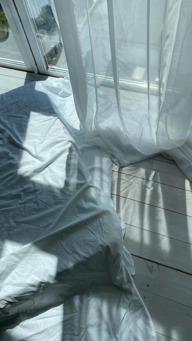 Bed near glass window in sunlight